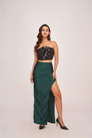 A glamorous co-ord set pairing a shimmering black crop top with a floor-length forest green skirt featuring a daring thigh-high slit.
