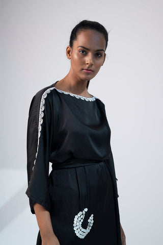 Close-up of black mini kimono dress with boat neck, shell embroidery, and kimono sleeves.