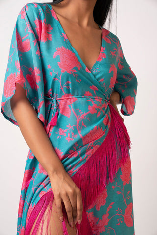 Close-up front view of model in blue floral muslin wrap dress with tassel detailing and V-neckline.