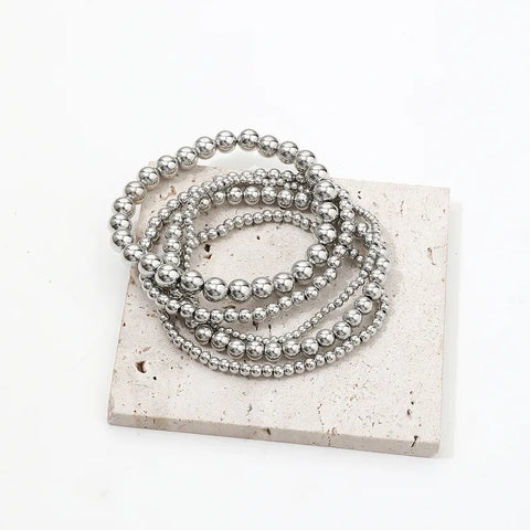 This versatile four-piece silver anklet set features a combination of minimalist chains and patterned beads, an ideal accessory for creating a curated, boho-chic look for summer festivals.