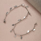 A refined sterling silver anklet featuring a series of polished, flat oval charms that catch the light, perfect for adding a sophisticated sparkle to  a cocktail party.
