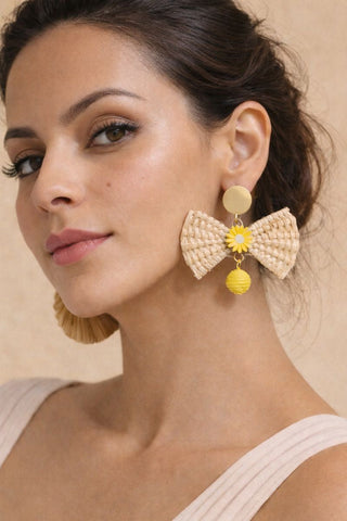 Raffia bow statement earrings with yellow floral accents, ideal for a bright, breezy brunch look or accessorizing a sundress.