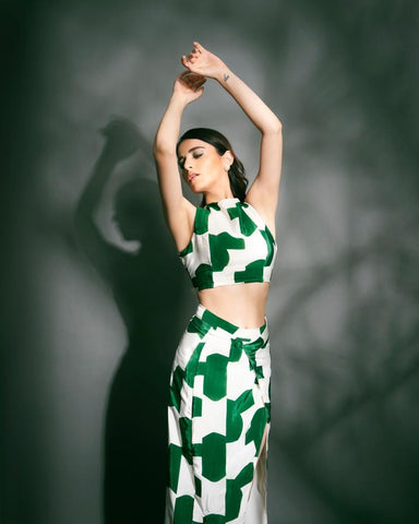 Model standing tall with both hands raised, showcasing the back tie-up and bold green abstract print of the summer co-ord set.